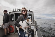 Portrait de femme souriante avec chien sur un bateau de pêche — Photo de stock