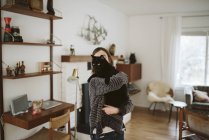 Menina segurando gato preto na sala de estar — Fotografia de Stock