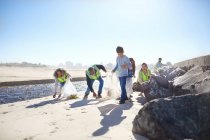 Добровольцы убирают мусор на солнечном пляже — стоковое фото