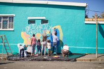Freiwillige der Gemeinde malen lebhaftes Wandgemälde an sonnige Stadtmauer — Stockfoto