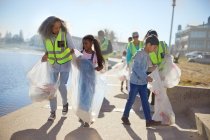 Freiwillige räumen Müll an sonniger Uferpromenade auf — Stockfoto