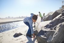 Хлопчик доброволець збирає сміття на сонячному пляжі — стокове фото