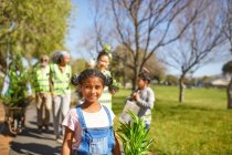 Портрет усміхнений, впевнена дівчина-волонтер, саджає дерева в сонячному парку — стокове фото