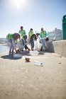 Volunteers picking up plastic litter on sunny boardwalk — Stock Photo