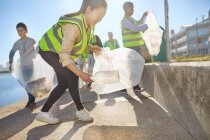 Woman volunteer picking up plastic litter on sunny boardwalk — Stock Photo