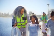 Grandmother and granddaughter volunteers picking up litter on boardwalk — Stock Photo