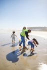 Freiwillige räumen Müll am sonnigen, nassen Sandstrand auf — Stockfoto