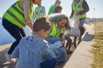 Freiwillige räumen Müll an sonniger Uferpromenade auf — Stockfoto