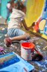 Mädchen bemalt Wandbild hinter Farbdose — Stockfoto
