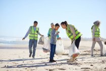 Волонтери прибирають сміття на сонячному, піщаному пляжі — стокове фото