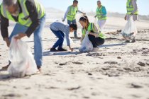 Mãe e filho voluntários limpando ninhada na praia ensolarada e arenosa — Fotografia de Stock