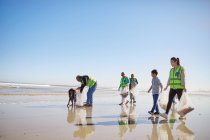 Voluntários limpando lixo da praia de areia molhada — Fotografia de Stock