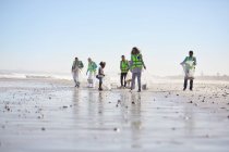 Волонтери прибирають сміття на сонячно вологому піщаному пляжі — стокове фото