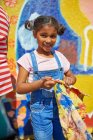 Retrato sorrindo menina pintura mural vibrante na parede ensolarada — Fotografia de Stock