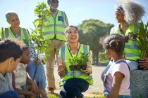 Happy volunteers planting trees and plants in sunny park — Stock Photo