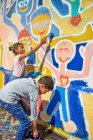 Kinder malen lebhaftes Wandbild an sonnige Wand — Stockfoto