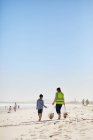 Мать и сын добровольцы убирают мусор на солнечном песчаном пляже — стоковое фото