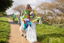 Portrait heureux femmes multi-générations bénévolat, nettoyer la litière dans un parc ensoleillé — Photo de stock