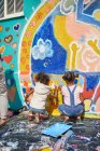 Девушки рисуют яркие фрески на солнечной стене — стоковое фото