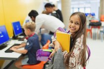 Portrait of smiling, confident junior student carrying books in library — Stock Photo