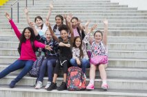 Portrait enthusiastic junior high girl students waving on steps — Stock Photo