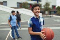 Porträt lächelt, selbstbewusster Junge spielt Basketball auf dem Schulhof — Stockfoto