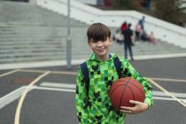 Retrato confiante tween menino com basquete no pátio da escola — Fotografia de Stock