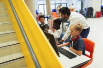 Lehrer hilft Realschülern beim Umgang mit Computern in der Bibliothek — Stockfoto