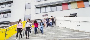 Estudiantes de secundaria abandonando el edificio de la escuela, pasos descendentes - foto de stock