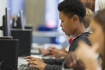 Фокусований молодший школяр, який використовує комп'ютер у комп'ютерній лабораторії — стокове фото