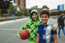 Retrato de felices amigos de secundaria jugando baloncesto en el patio de la escuela - foto de stock