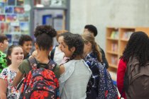 Estudiantes de secundaria hablando en la biblioteca - foto de stock