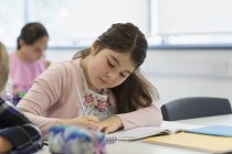 Сосредоточенный ученик средней школы делает домашнее задание в классе — стоковое фото
