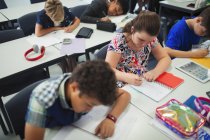 Studenti delle scuole medie che fanno i compiti alle scrivanie in classe — Foto stock