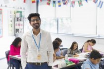 Porträt lächelnder, selbstbewusster männlicher Lehrer im Klassenzimmer — Stockfoto