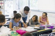 Чоловічий вчитель, який допомагає молодшим школярам за столом у класі — стокове фото
