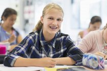 Portrait smiling, enthusiastic junior high school girl student with braces in classroom — Stock Photo