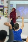 Profesora en hijab liderando la lección en la pantalla de proyección en el aula - foto de stock