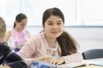 Портрет впевнена молодша школярка робить домашнє завдання в класі — стокове фото