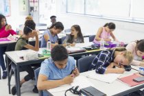 Junior high school students studying at desks in classroom — Stock Photo