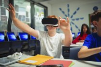 Curioso estudiante de secundaria utilizando simulador de realidad virtual en el aula - foto de stock
