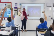 Женщина-учитель в хиджабе, ведущий урок, призывает учеников в классе — стоковое фото