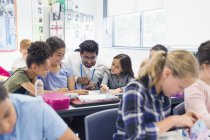 Учитель помогает ученикам младших классов за столом в классе — стоковое фото