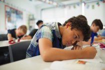 Сосредоточенные школьники делают домашнее задание в классе — стоковое фото