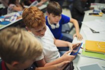 Junior high school boy students using digital tablets at desk in classroom — Stock Photo