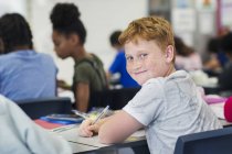 Retrato de sorridente, confiante estudante do ensino médio júnior estudando na mesa em sala de aula — Fotografia de Stock