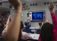 Estudantes do ensino médio que participam com as mãos levantadas na sala de aula — Fotografia de Stock