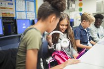 Junior high school student removing headphones from backpack in classroom — Stock Photo