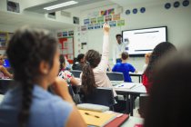 Estudante do ensino médio levantando a mão, fazendo uma pergunta durante a aula em sala de aula — Fotografia de Stock