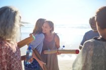 Freundinnen mit Yogamatten umarmen sich am sonnigen Strand beim Yoga-Retreat — Stockfoto